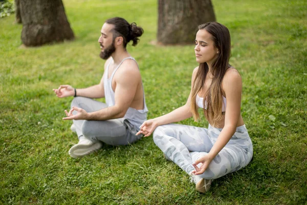 Pareja joven haciendo yoga al aire libre — Foto de Stock