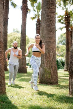 Yaz sabahı parkta koşan genç bir çift.