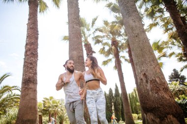 Yaz sabahı parkta koşan genç bir çift.