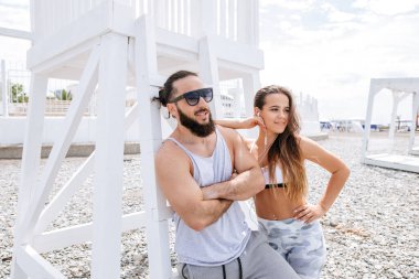 Genç çift, çakıl taşlı plajda dinlenirken kulaklıkla müzik dinliyor.