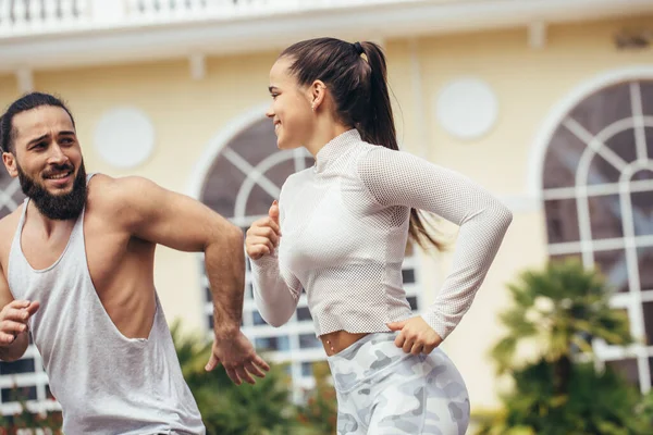 Fitness, deporte, personas y concepto de estilo de vida - pareja feliz con auriculares corriendo al aire libre — Foto de Stock