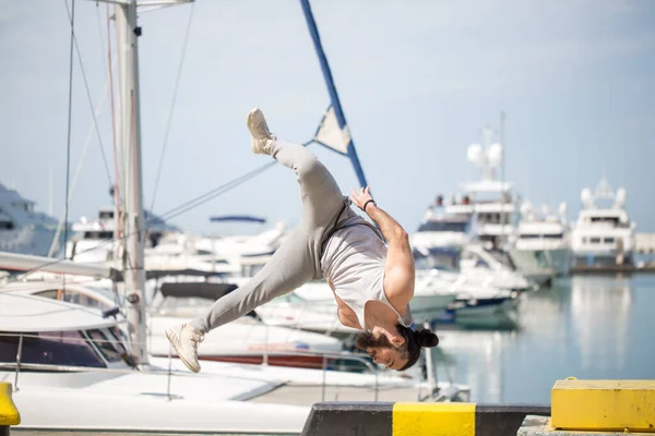 Fitness athlete doing jump squats on makeshift plyo-box on summer sea pier