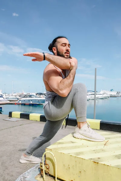 Sportler mit trendiger Frisur, die sich am Seebrücke ausdehnt — Stockfoto