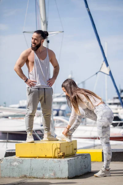 Joven pareja deportiva teniendo un descanso entre el entrenamiento, preparándose para correr en el muelle. — Foto de Stock