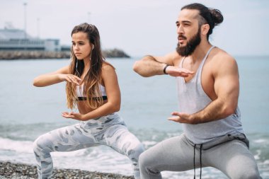 Dışarıda ısınan çiftler, birlikte çömelme hareketleri yapıyorlar.