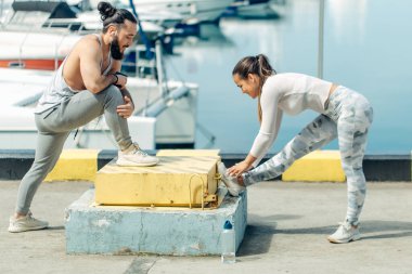 Genç ve güzel bir çift okyanus rıhtımında esneme egzersizleri yapıyor.
