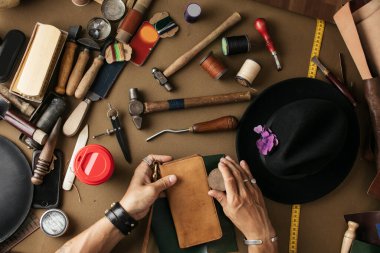 Bir atölyede deri tekstil ve çekiçle çalışan bir kunduracının önünde.