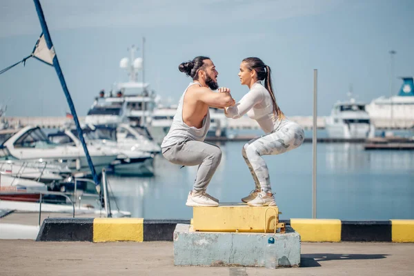 Atleta femenino y masculino está realizando saltos de caja al aire libre. — Foto de Stock