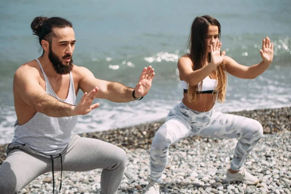 Dışarıda ısınan çiftler, birlikte çömelme hareketleri yapıyorlar.