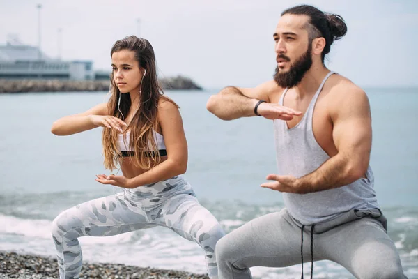 Dışarıda ısınan çiftler, birlikte çömelme hareketleri yapıyorlar.