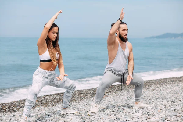 Dışarıda ısınan çiftler, birlikte çömelme hareketleri yapıyorlar.