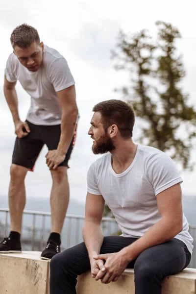 Två idrottare vilar efter intensiv utomhus träning i bergslandskapet — Stockfoto