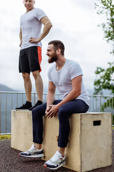 Dos atletas descansan después de un intenso entrenamiento al aire libre en el paisaje de montaña — Foto de Stock