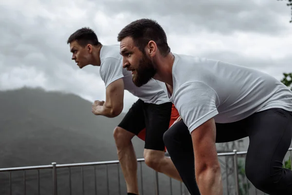 Entrenamiento matutino, hombres deportivos corriendo por las montañas viviendo un estilo de vida saludable — Foto de Stock
