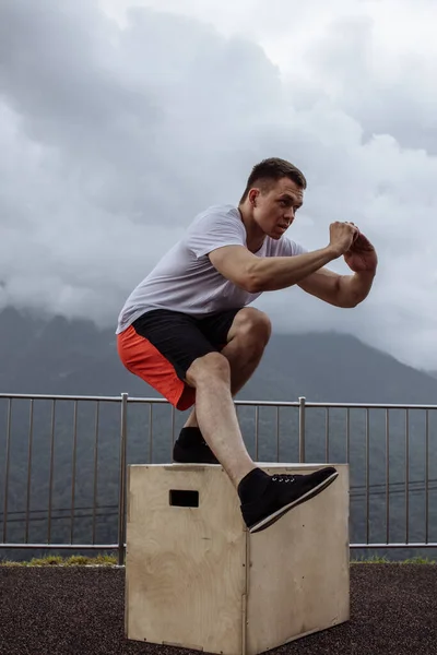 Musculat chicos mostrando una pierna ejercicio en cuclillas, de cerca, entrenamiento al aire libre — Foto de Stock