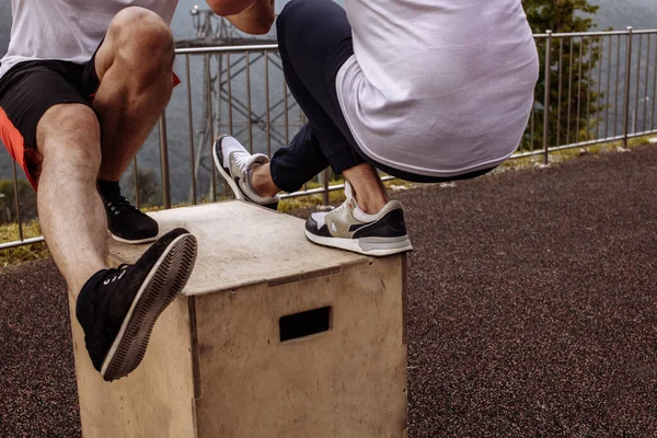 Muskulat killar visar ett ben knäböj motion, närbild, utomhus träning — Stockfoto
