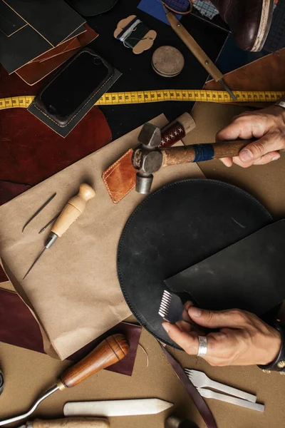 Крупный план ремесленника, работающего с натуральной кожей с использованием ремесленных инструментов. — стоковое фото