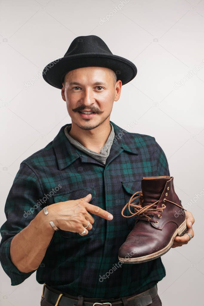 Photo of young cheerful shoemaker holding self made shoe isolated over white.