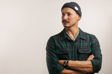 El sanatları ustası, kollarını katlayarak beyaz duvarın üzerinde tek başına dikiliyor..