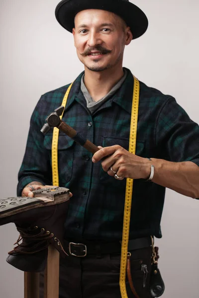 Retrato de sapateiro alegre martelando em um sapato. — Fotografia de Stock