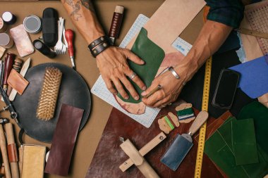 Bir atölyede deri tekstil ve çekiçle çalışan bir kunduracının önünde.