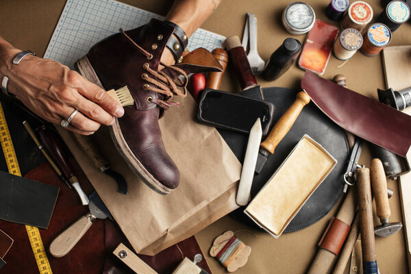 Close up of shoe maker hands producing boots in his leather workshop