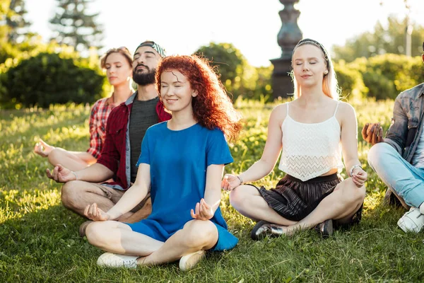 Groep volwassen vrienden mediteren tijdens yoga buiten in het park. — Stockfoto