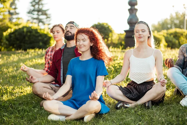 Groep volwassen vrienden mediteren tijdens yoga buiten in het park. — Stockfoto