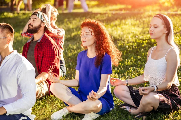 Groep volwassen mix-race vrienden mediteren tijdens yoga buiten in het park. — Stockfoto