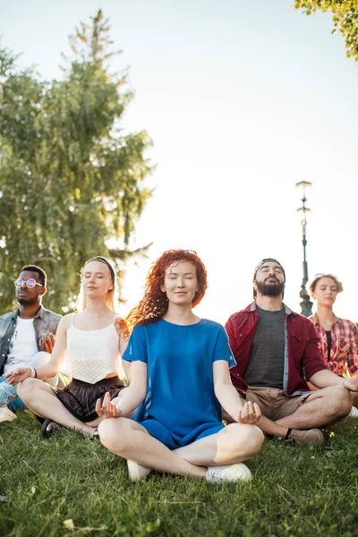 一群混合种族的成年朋友在公园外练习瑜伽时冥想. — 图库照片