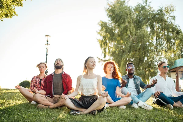 一群混合种族的成年朋友在公园外练习瑜伽时冥想. — 图库照片