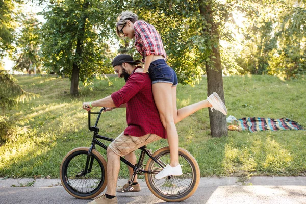 情侣们在公园里自由自在地骑着一辆自行车，在阳光明媚的夏日玩得很开心. — 图库照片