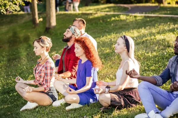 Groep volwassen vrienden mediteren tijdens yoga buiten in het park. — Stockfoto