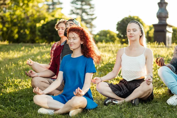 Groep volwassen vrienden mediteren tijdens yoga buiten in het park. — Stockfoto