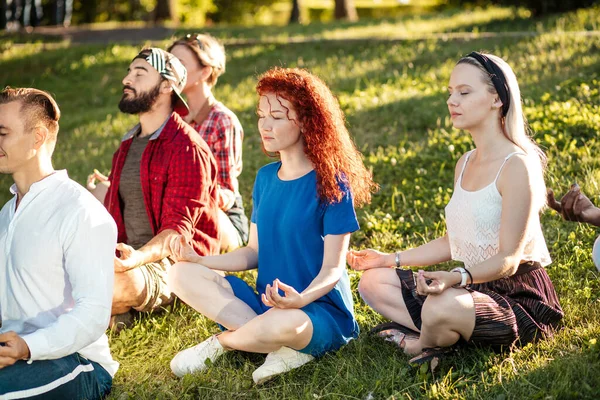 Groupe d'amis adultes méditant tout en pratiquant le yoga dehors dans le parc. — Photo