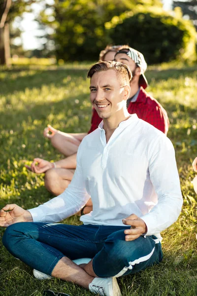 Groupe de personnes multiethniques faisant de l'exercice au parc, profitant de séances de yoga en plein air. — Photo