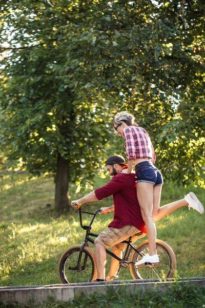 情侣们在公园里自由自在地骑着一辆自行车，在阳光明媚的夏日玩得很开心. — 图库照片