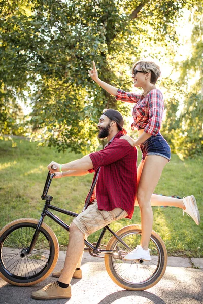 Joyeux jeune couple faisant une balade à vélo lors d'une journée d'été dans le parc. — Photo