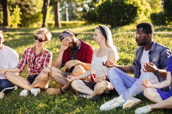 Groep volwassen vrienden mediteren tijdens yoga buiten in het park. — Stockfoto