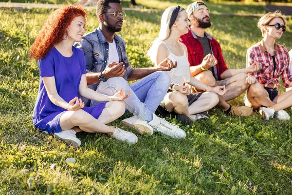 Groep volwassen vrienden mediteren tijdens yoga buiten in het park. — Stockfoto