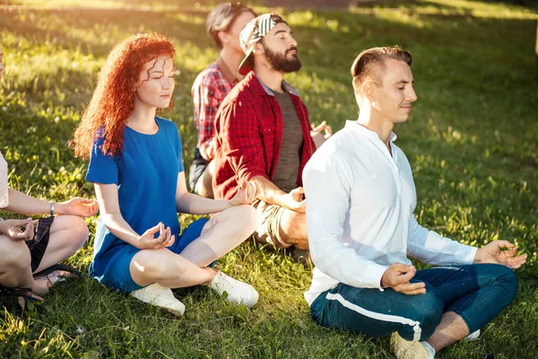 Groep volwassen vrienden mediteren tijdens yoga buiten in het park. — Stockfoto