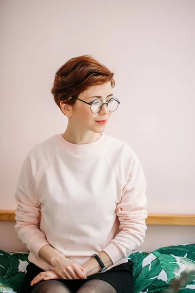 Porträt einer Frau mittleren Alters, die zu Hause eine Brille auf rosa Hintergrund trägt — Stockfoto