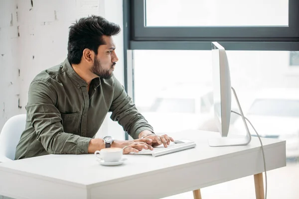 Indiaanse man werken aan de computer van moderne heldere kantoor — Stockfoto