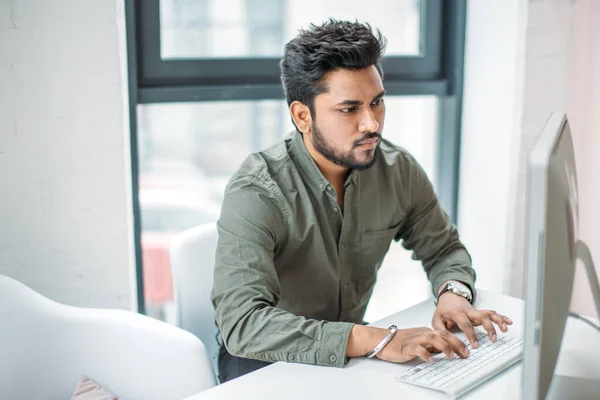 Indiaanse man werken aan de computer van moderne heldere kantoor — Stockfoto