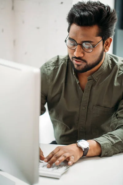 Indiaanse man werken aan de computer van moderne heldere kantoor — Stockfoto