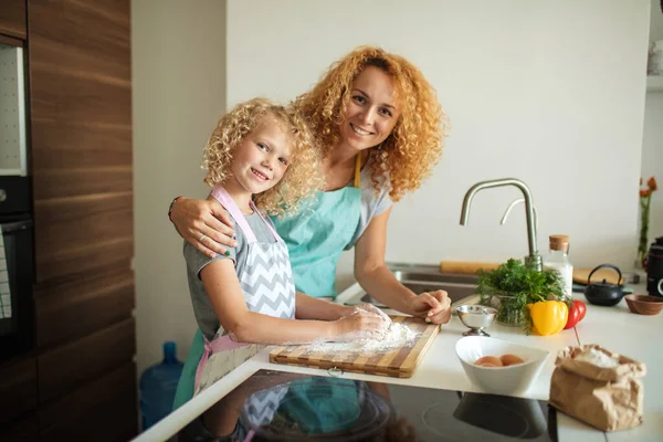 Frau und süße Tochter kochen in Küche und machen Teig für Geburtstagsparty. — Stockfoto