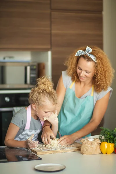 Frau und süße Tochter kochen in Küche und machen Teig für Geburtstagsparty. — Stockfoto