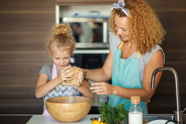 Kleines Mädchen und ihre Mutter streuen Mehl in eine Schüssel und lächeln beim Backen — Stockfoto
