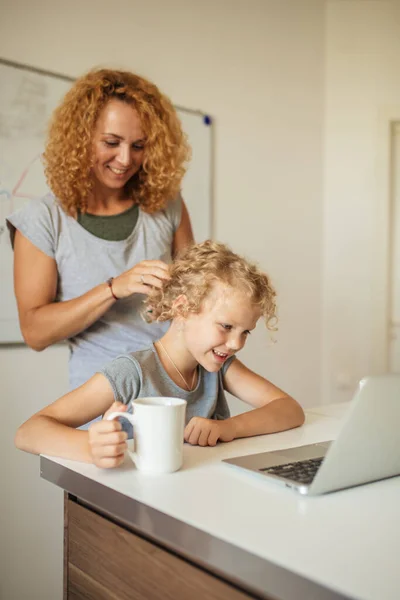 Usmívající se matka pomáhá její roztomilé dceři s domácím úkolem v obývacím pokoji — Stock fotografie