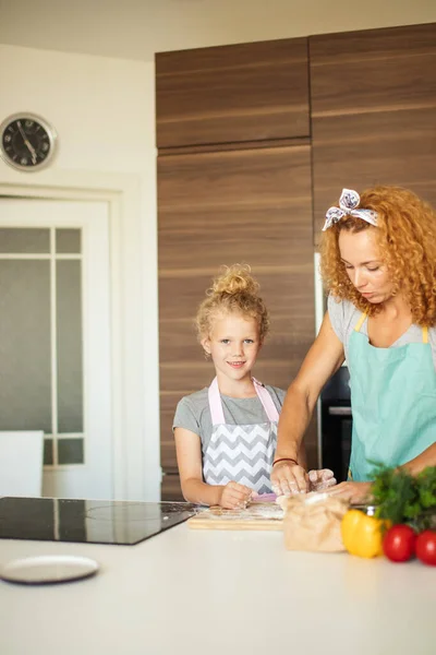 Young mom and little daughter smiling while baking in kitchen at home — ストック写真